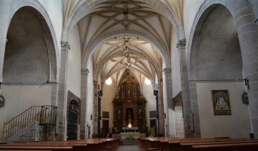 Interior de una iglesia de tres naves. Se ven tres tramos de la nave central más el presbiterio al fondo, cubiertos con bóveda de crucería. Al fondo del presbiterio, un retablo.
